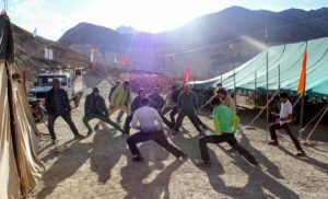 A group of people excercising with mountains in the background and sunrise.