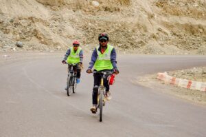 Two men wearing reflective vests riding bicycles on a road