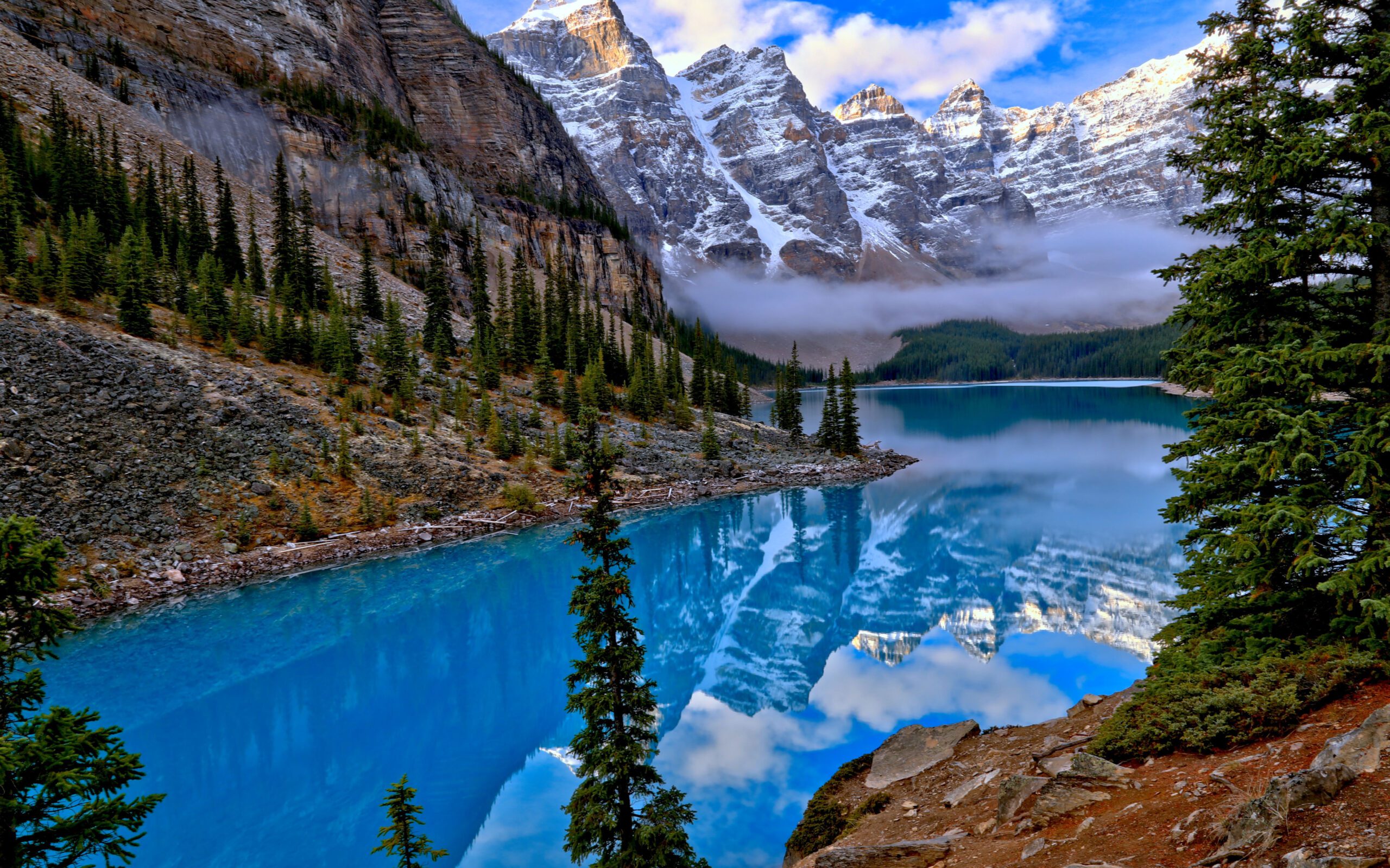 a lake with trees and mountains in the background