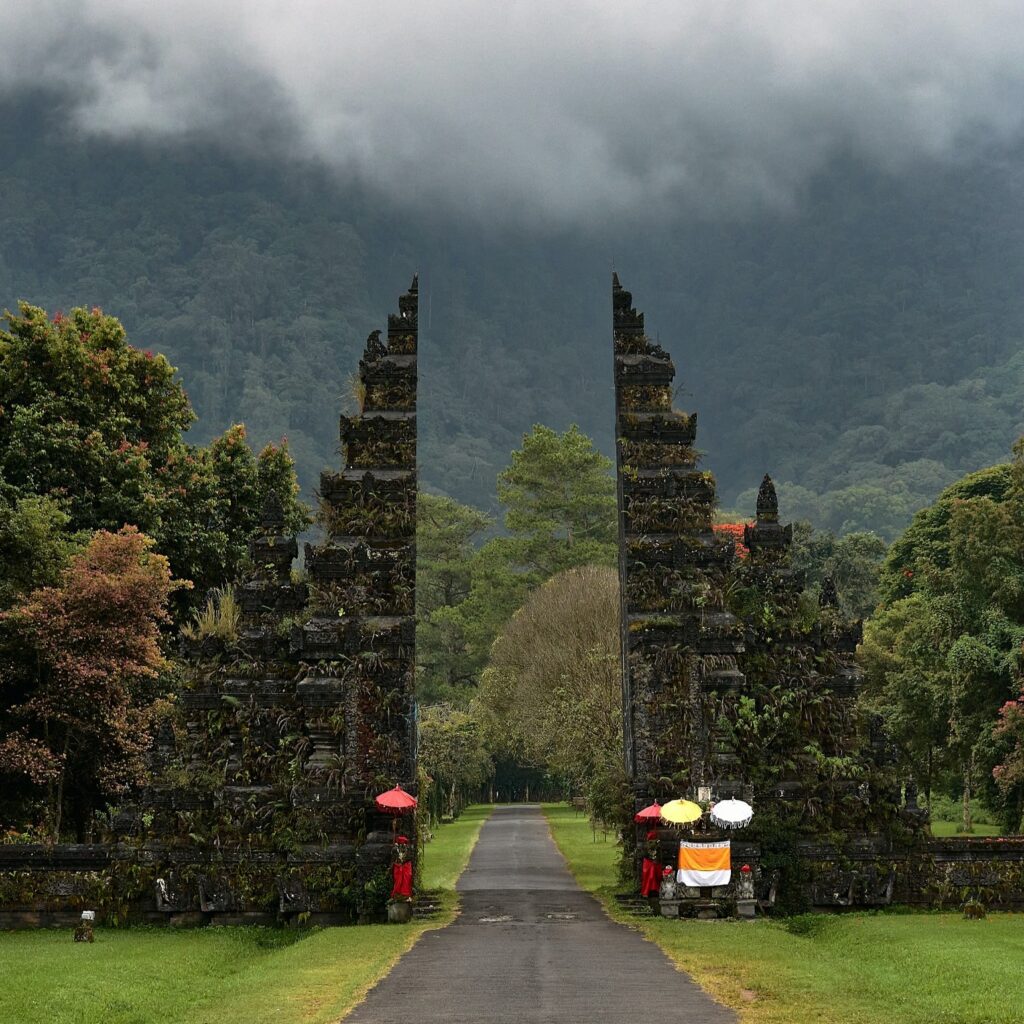 a stone gate with trees and a cloudy sky