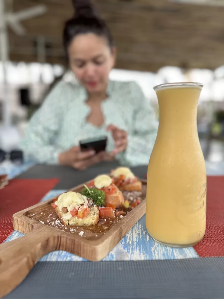 A plate of food and drink with a person in background