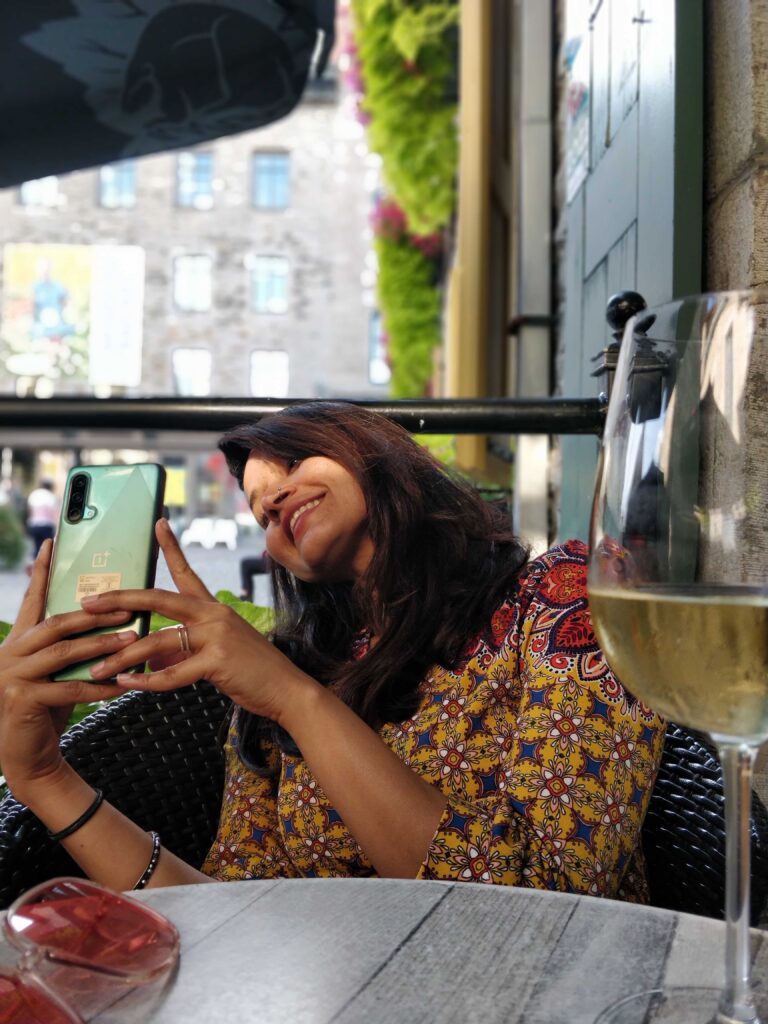 A person smiling at a glass of wine