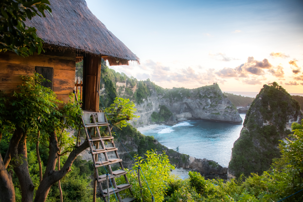 A house with a ladder on top of a cliff overlooking a body of water