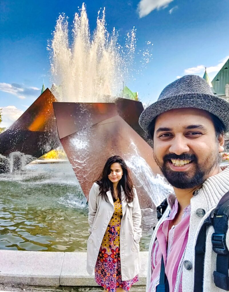 A person and person posing for a picture in front of a fountain