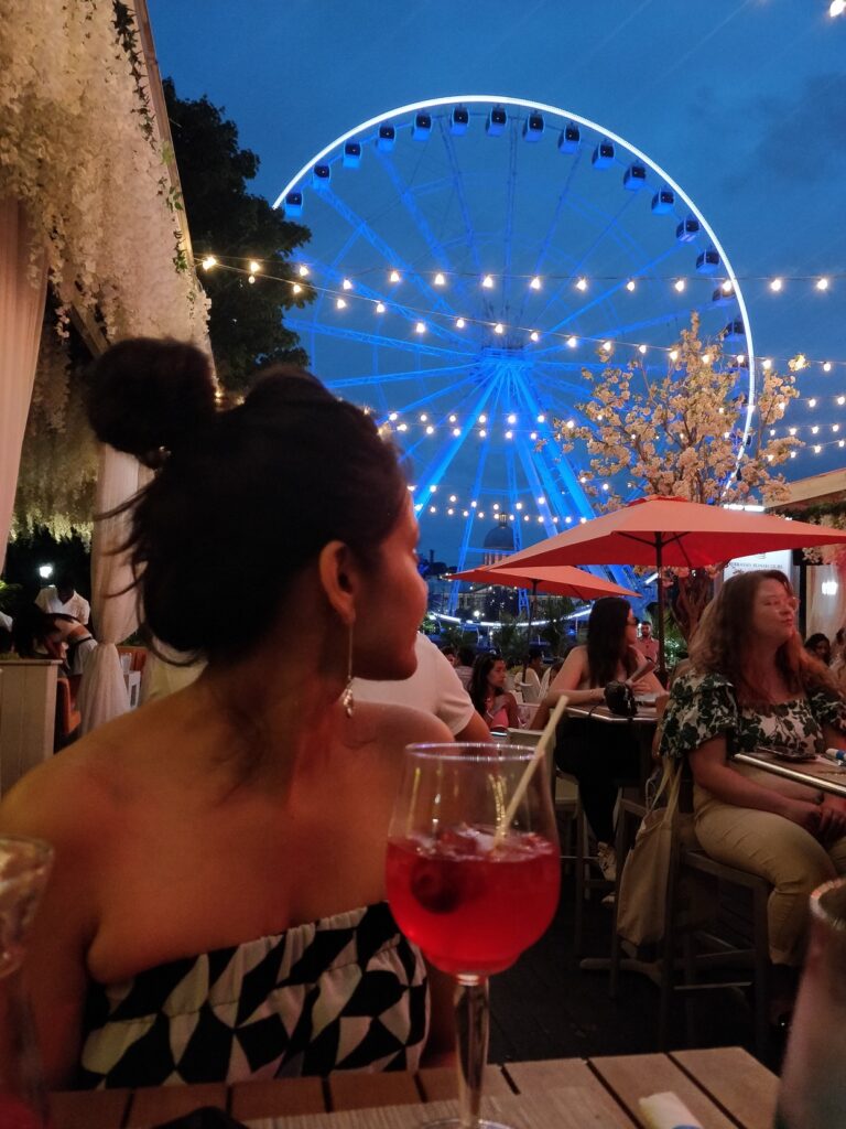 A person sitting at a table with a ferris wheel in the background