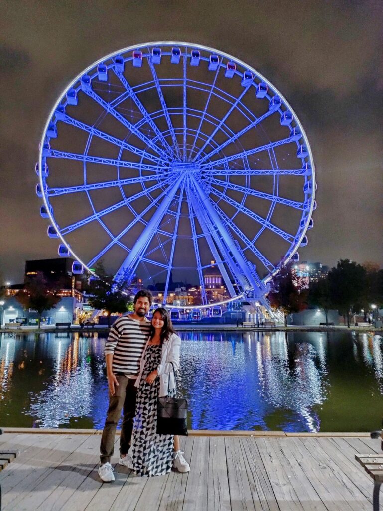 A person and person posing for a picture with a ferris wheel in the background