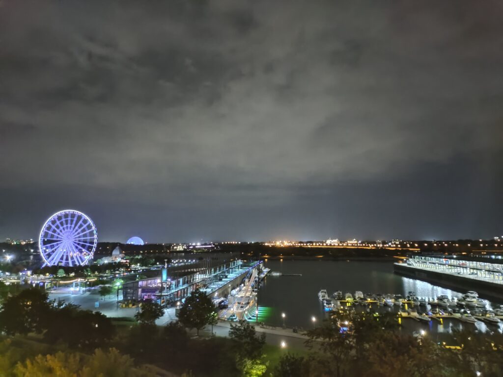 A city at night with a ferris wheel and a body of water