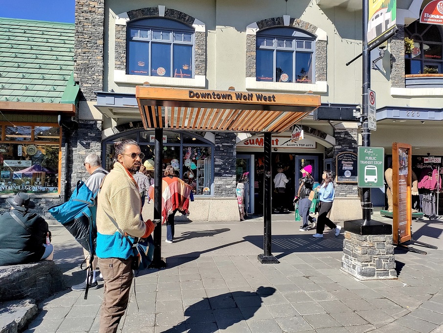 A person standing in front of a building and bus stop