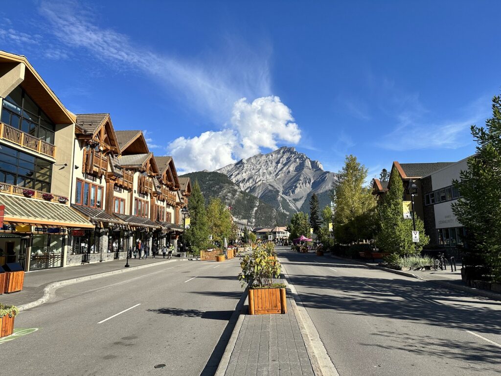 A street with buildings and trees in front of a mountain