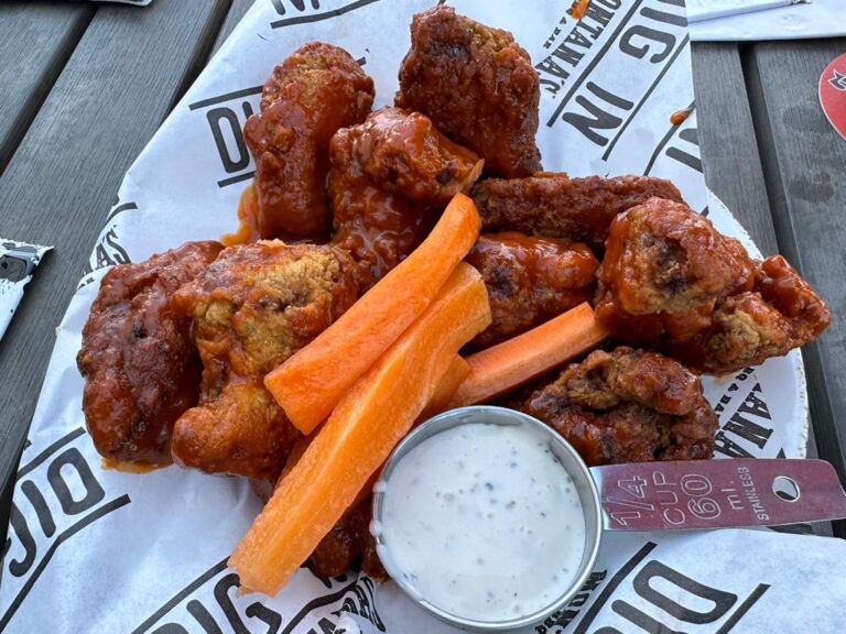 A plate of chicken wings and carrots on a table.