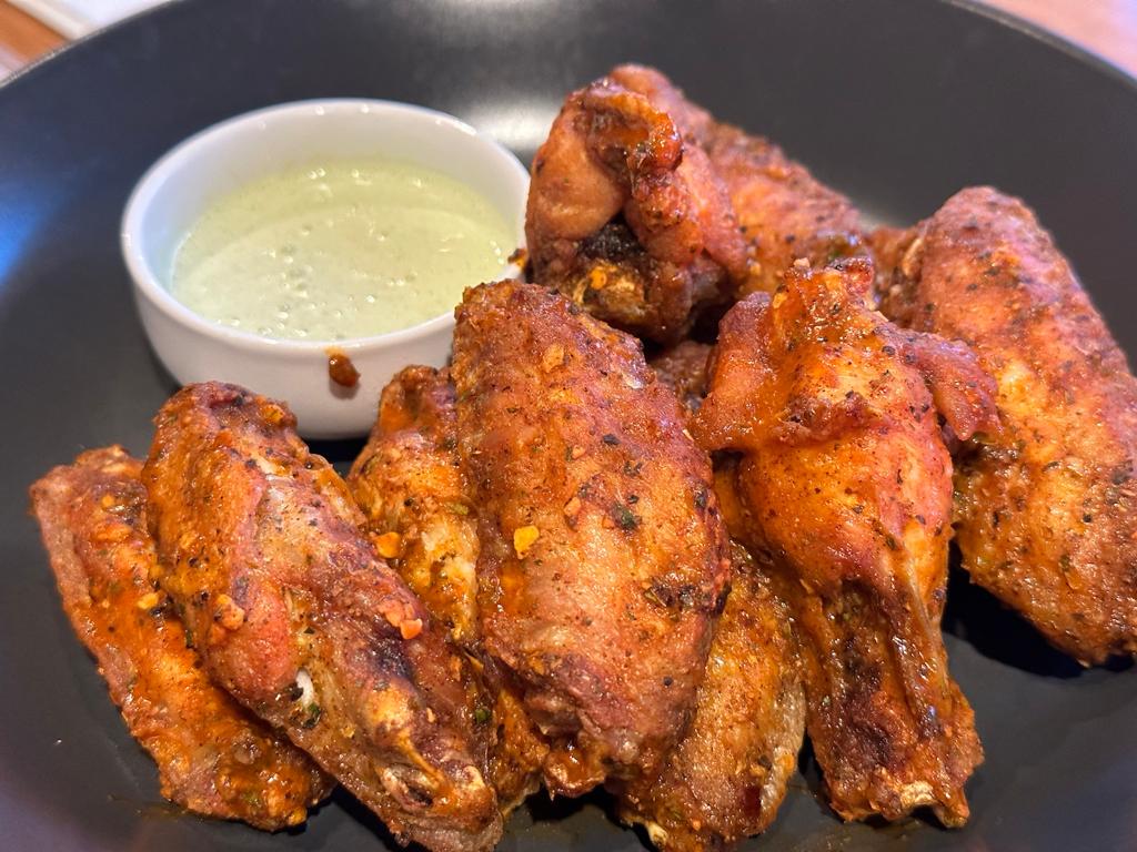 A plate of chicken wings with dipping sauce.