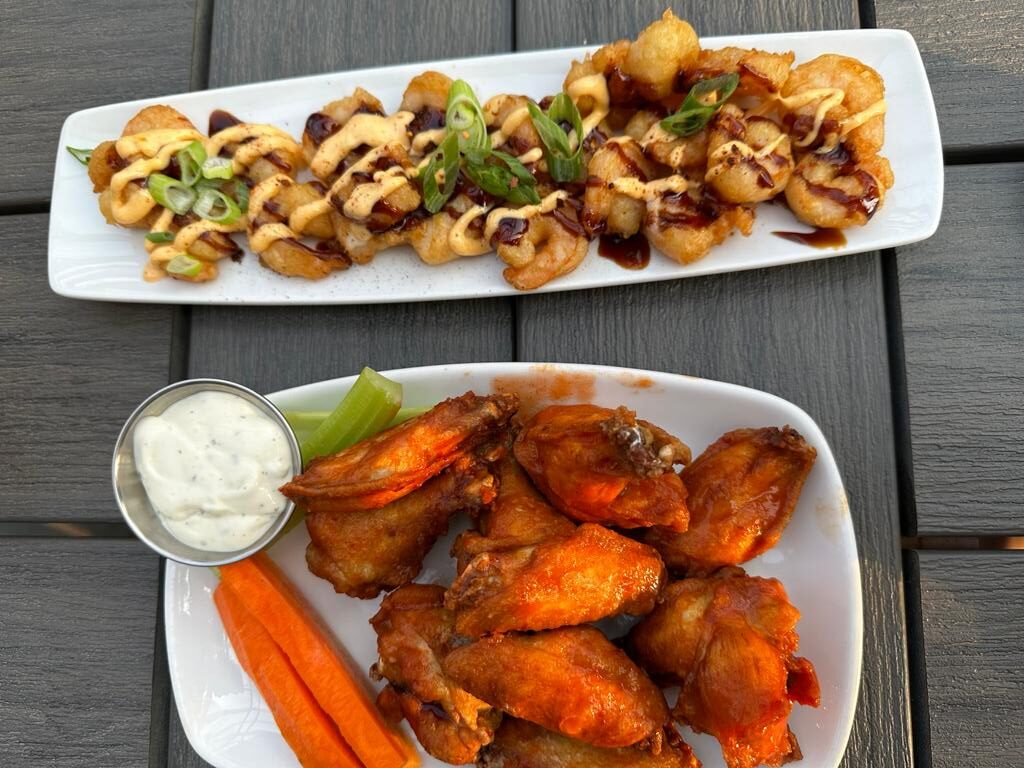 A plate of wings and carrots on a table.