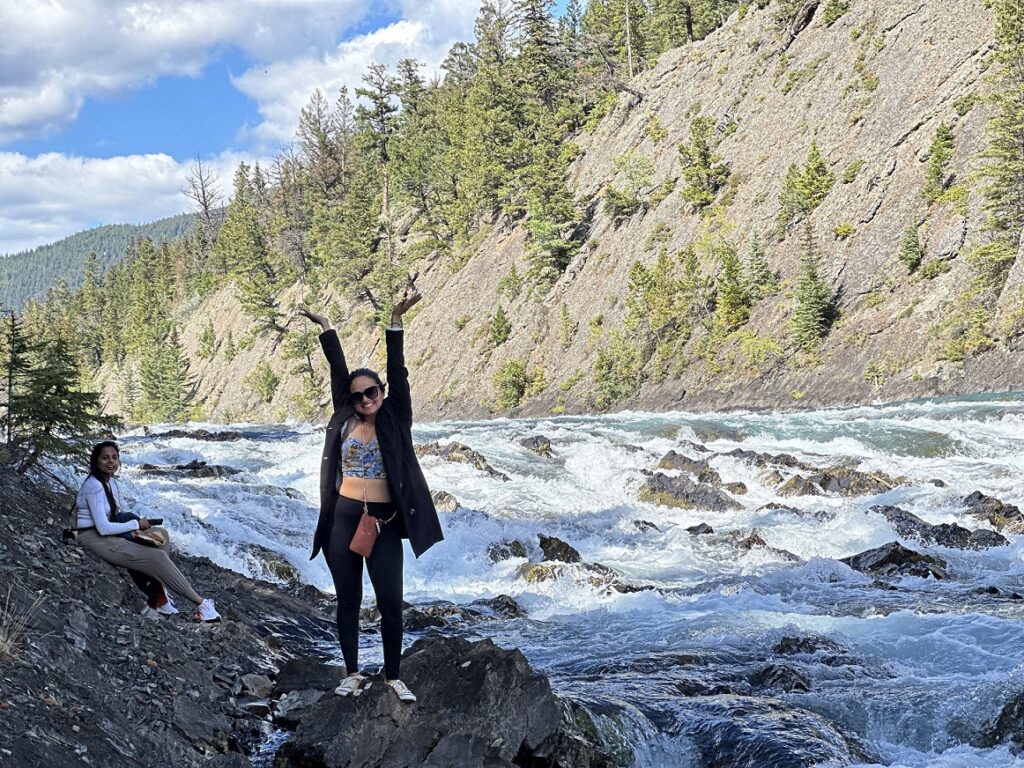 A person standing on rocks with her hands up in the air