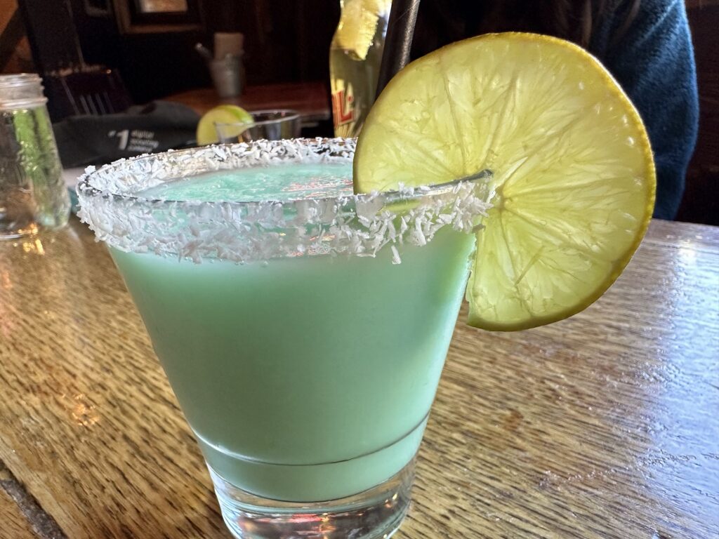 A glass with a blue drink and a slice of lemon on top