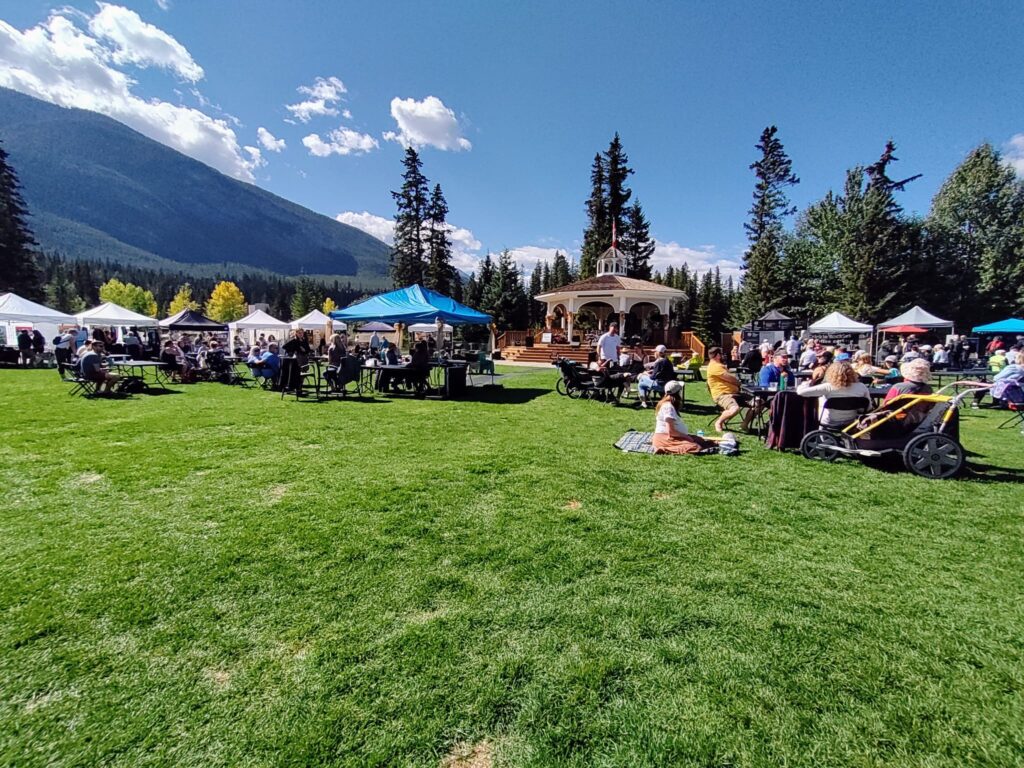 A group of people sitting on grass in front of a mountain