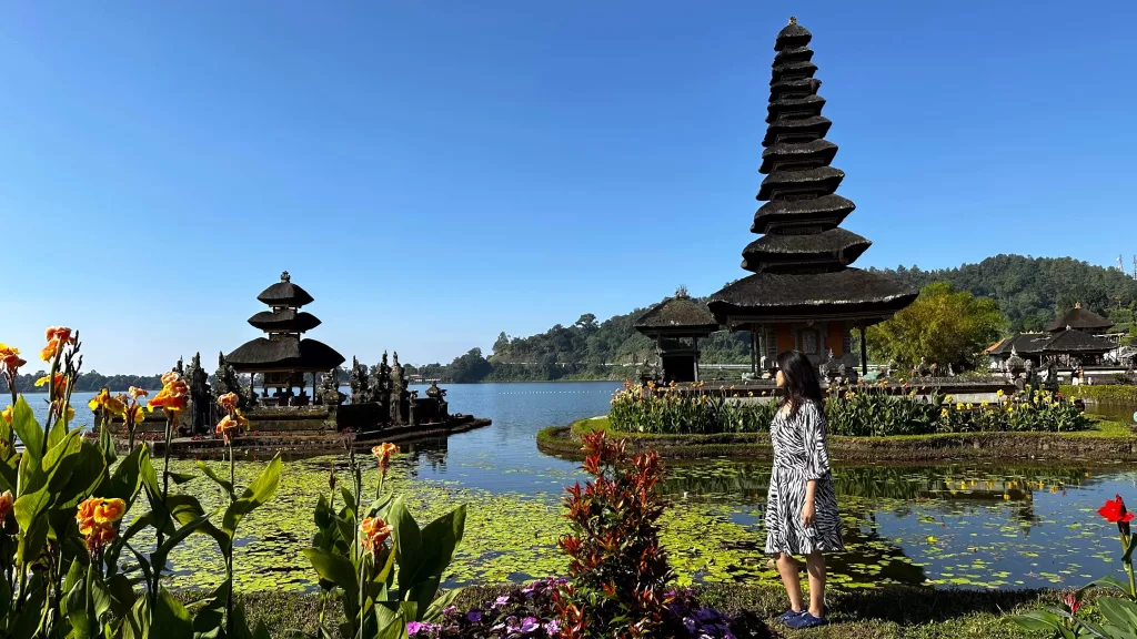 A person standing in front of a lake with a tall tower