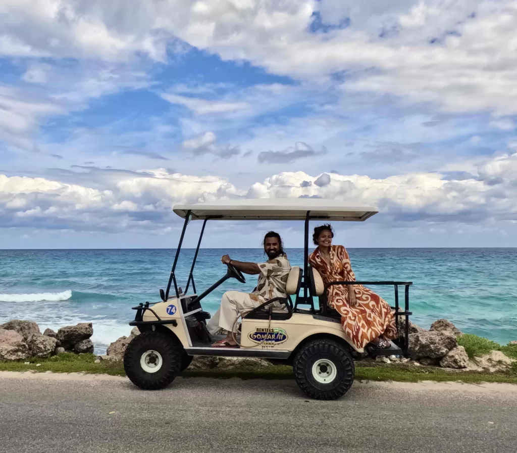 A person and person in a golf cart with ocean in the background.