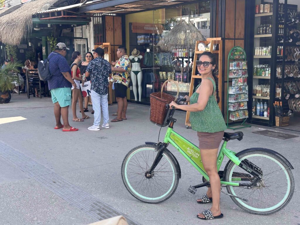 A person on a bike, in front of street shops.