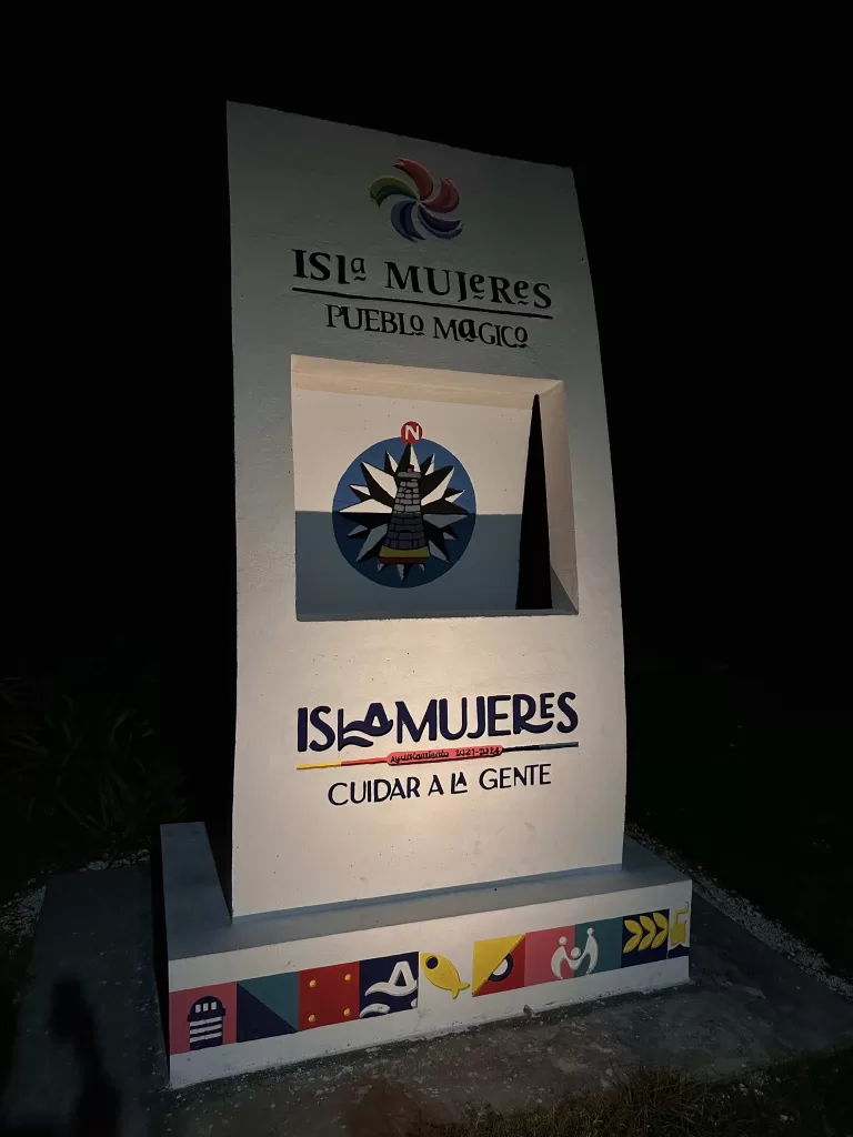 A sign with a square window depicting the Magical Town of Isla Mujeres