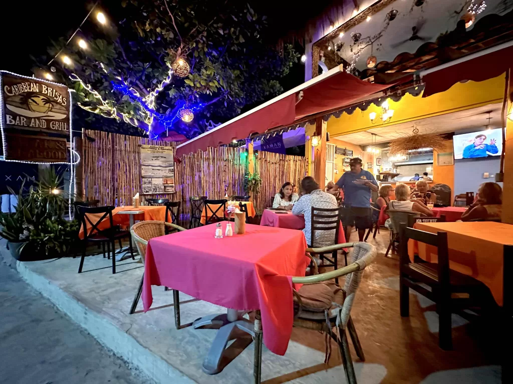 A group of people sitting at tables outside a restaurant