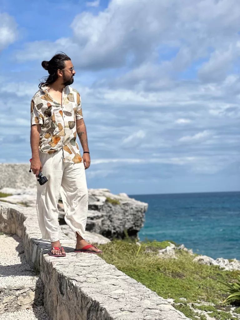 A person standing on a stone ledge by the ocean