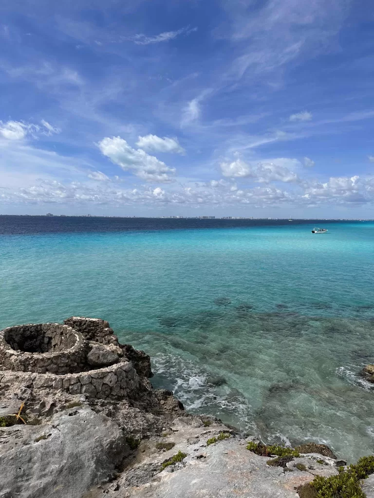 A rocky beach with blue water and a boat