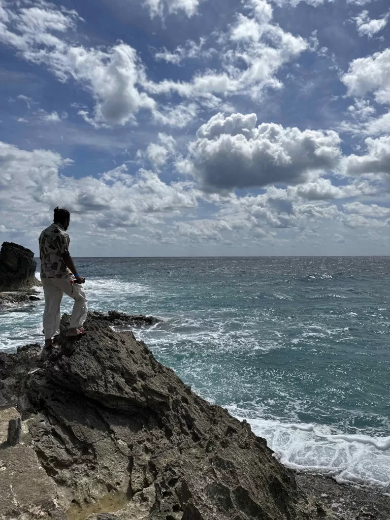 A person standing on a rock by the ocean. In Punta Sur