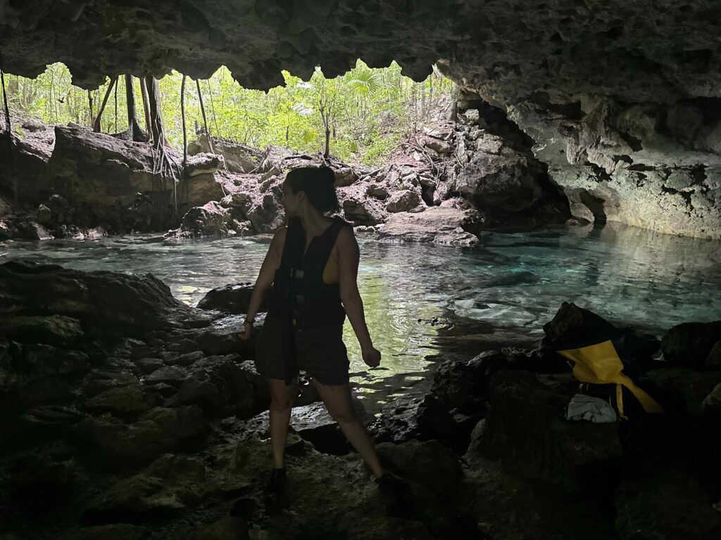 A person standing in front of a cave cenote