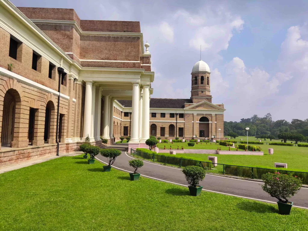 A large brick building with a lawn and a building with a tower