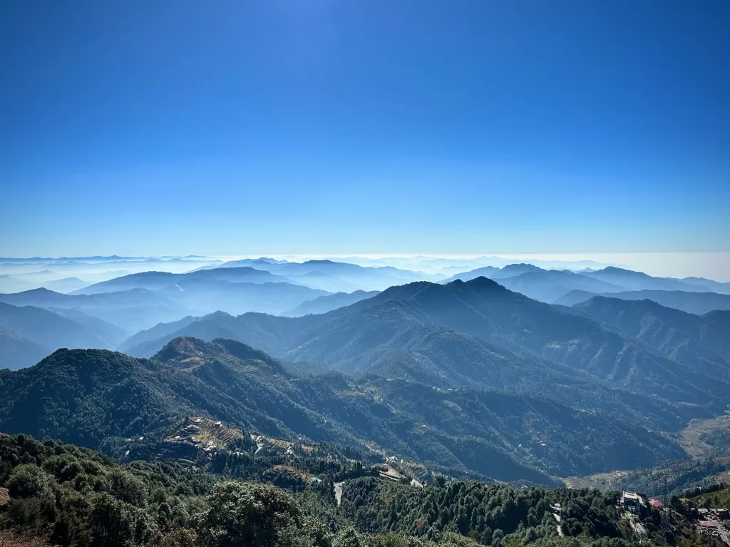 A landscape of mountains with trees and blue sky