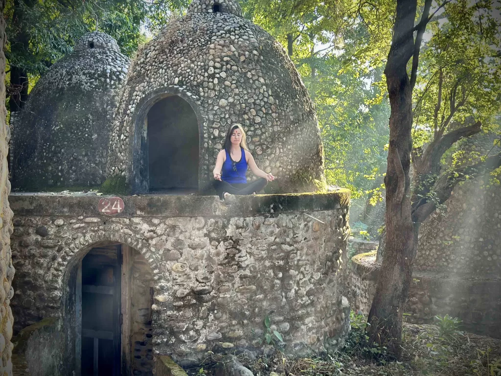 A person sitting on a stone structure. 84 huts in Beatles Ashram