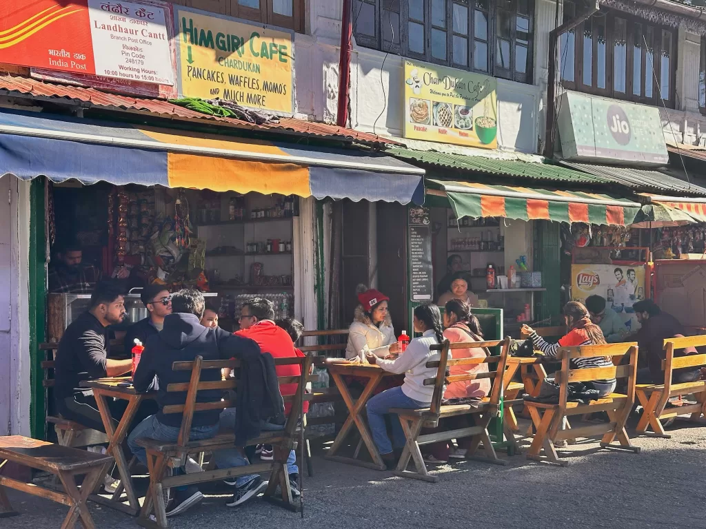 A group of people sitting at tables outside a restaurant