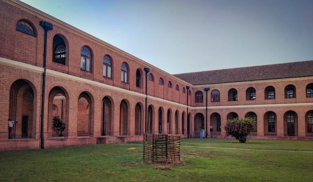 A large brick building names Forest Research Institute Dehradun with a lawn in front