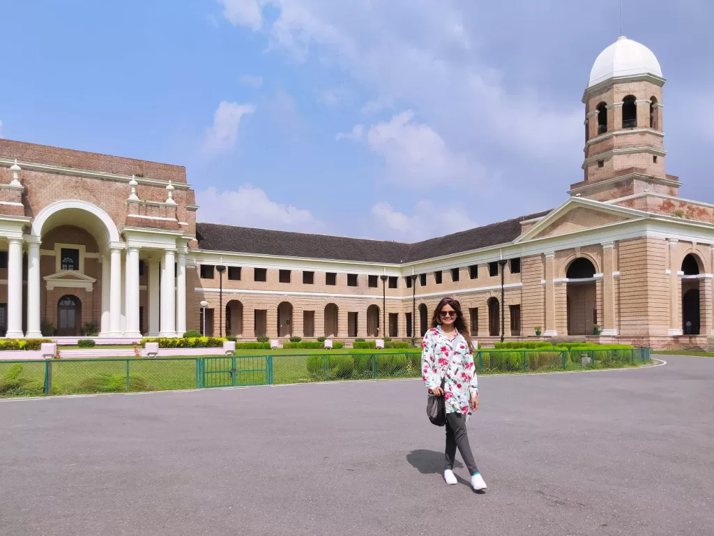 A person posing in front of a large building