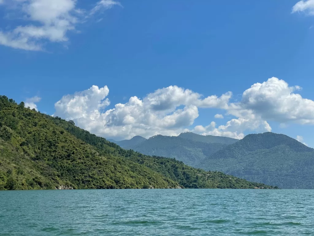 A body of water with trees and mountains in the background