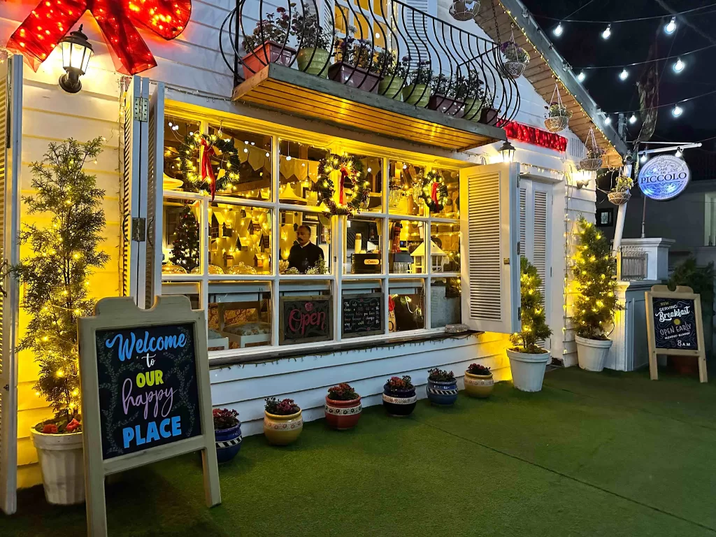 A store front with a sign and plants on the ground