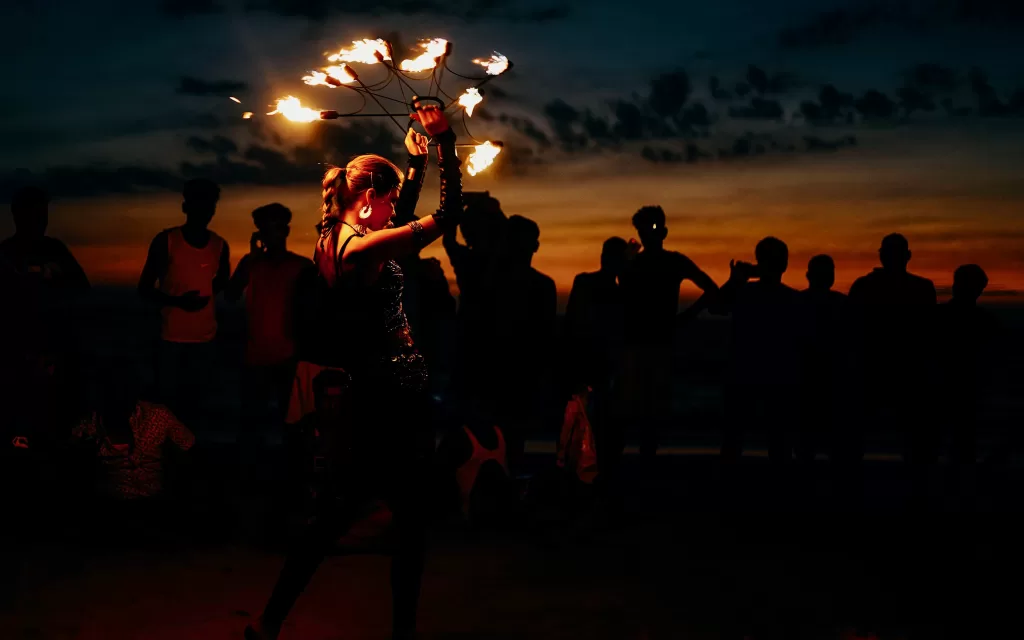 A person holding fire juggling with people watching