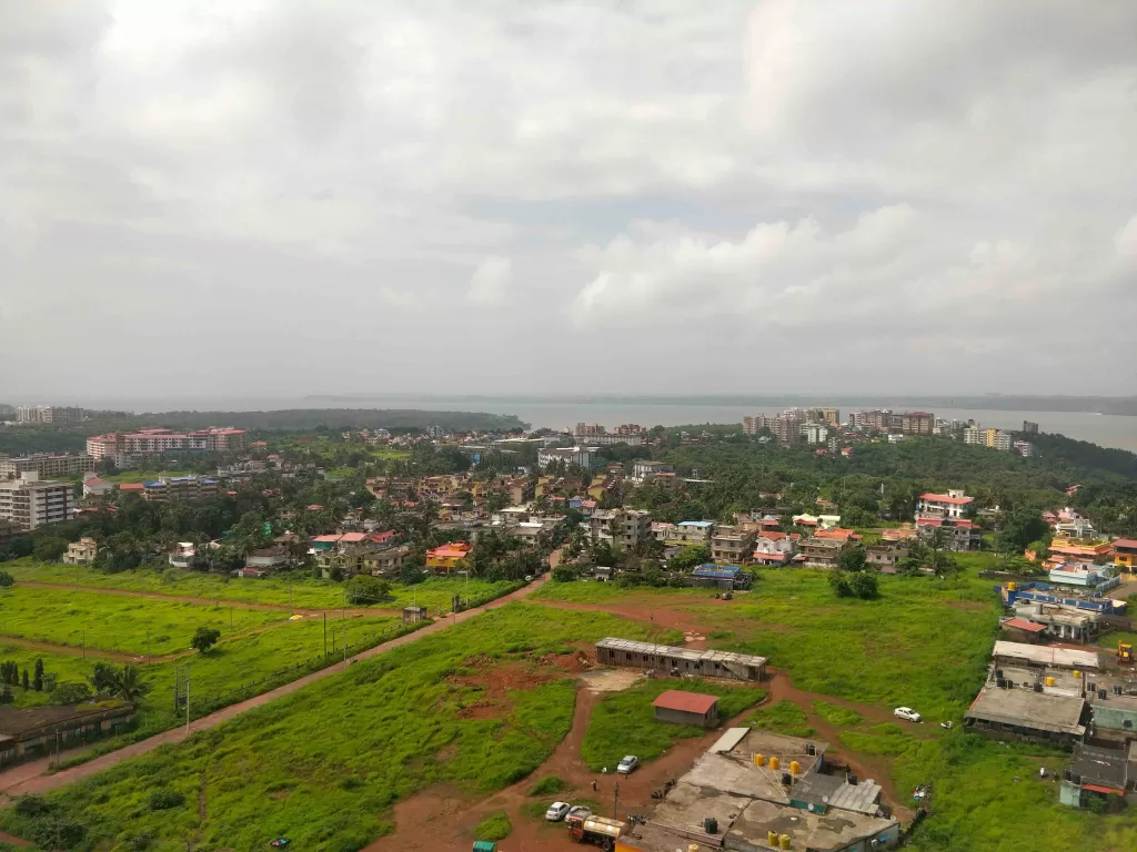 A green field with buildings and trees