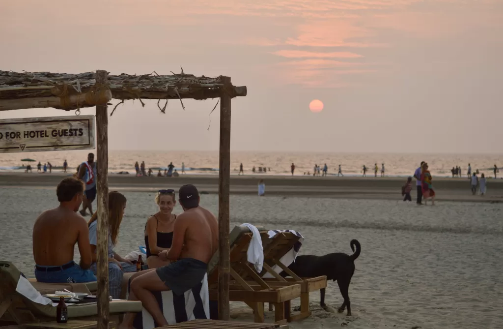 People sitting on a beach and enjoying sunset.