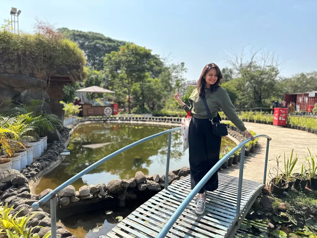 A person standing on a bridge over a pond.