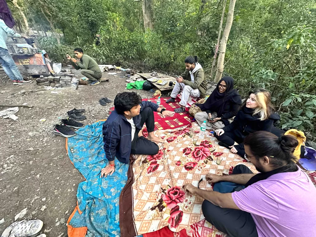 A group of people sitting on a blanket in the woods