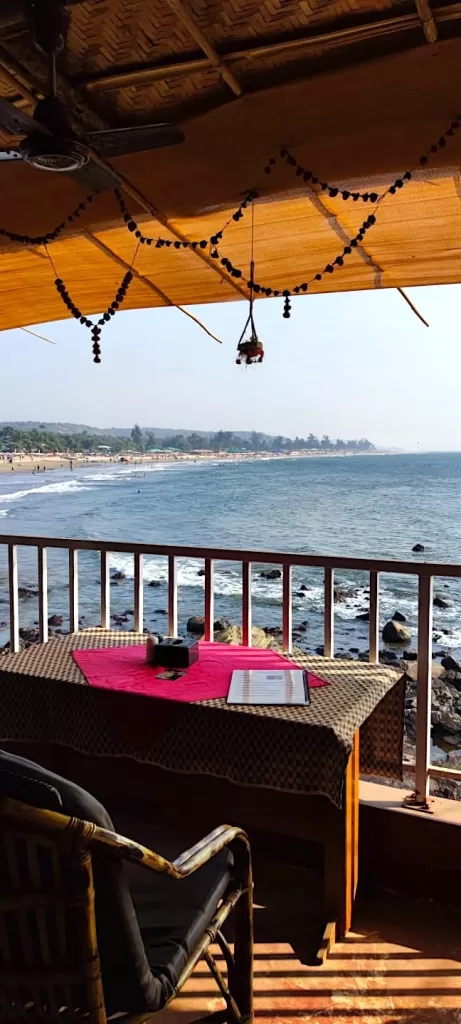 A table with a red cloth on it overlooking a beach. Hostels in Goa