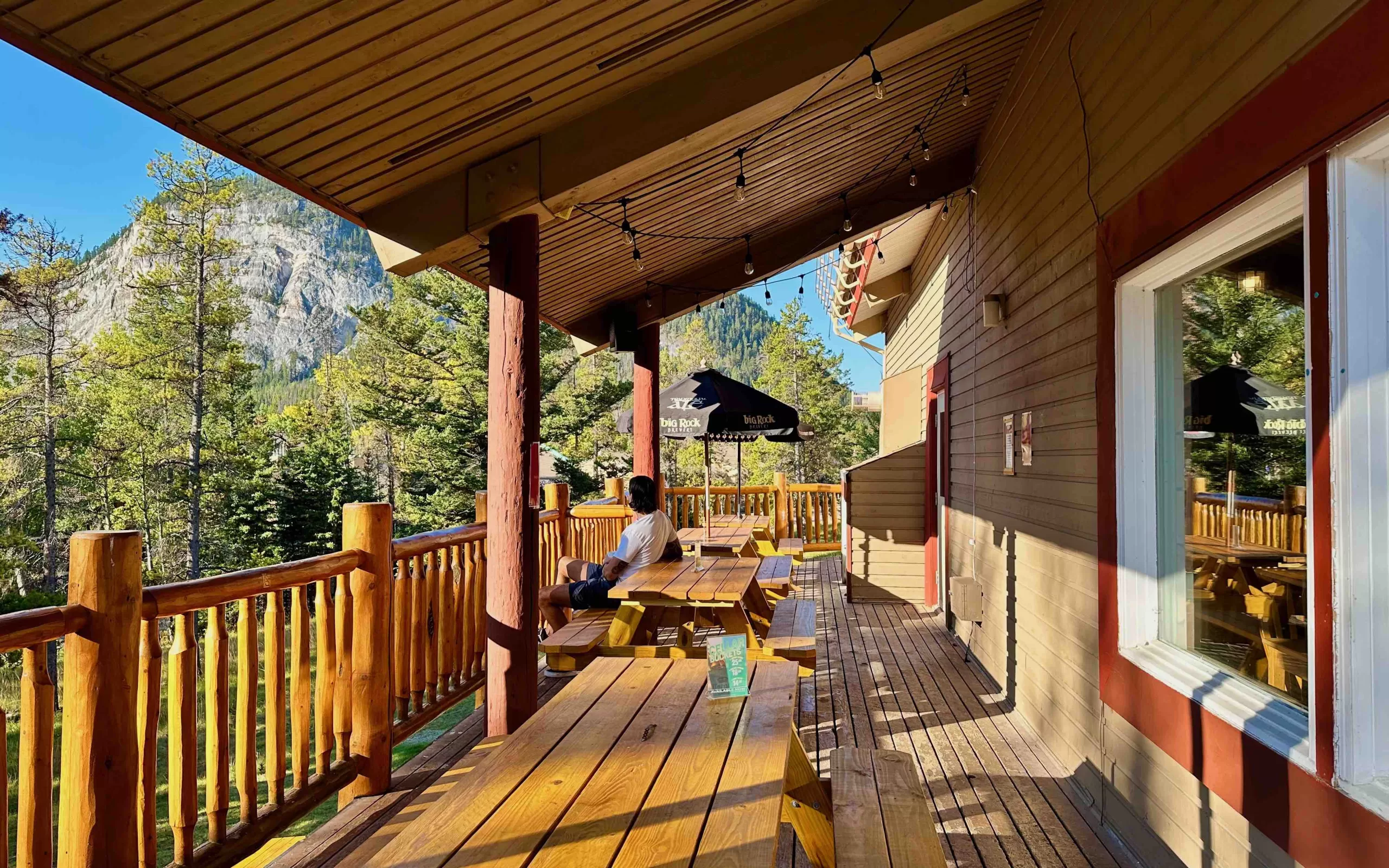 A person sitting on a wooden deck. Stay in hostels to experience the beauty of travel.