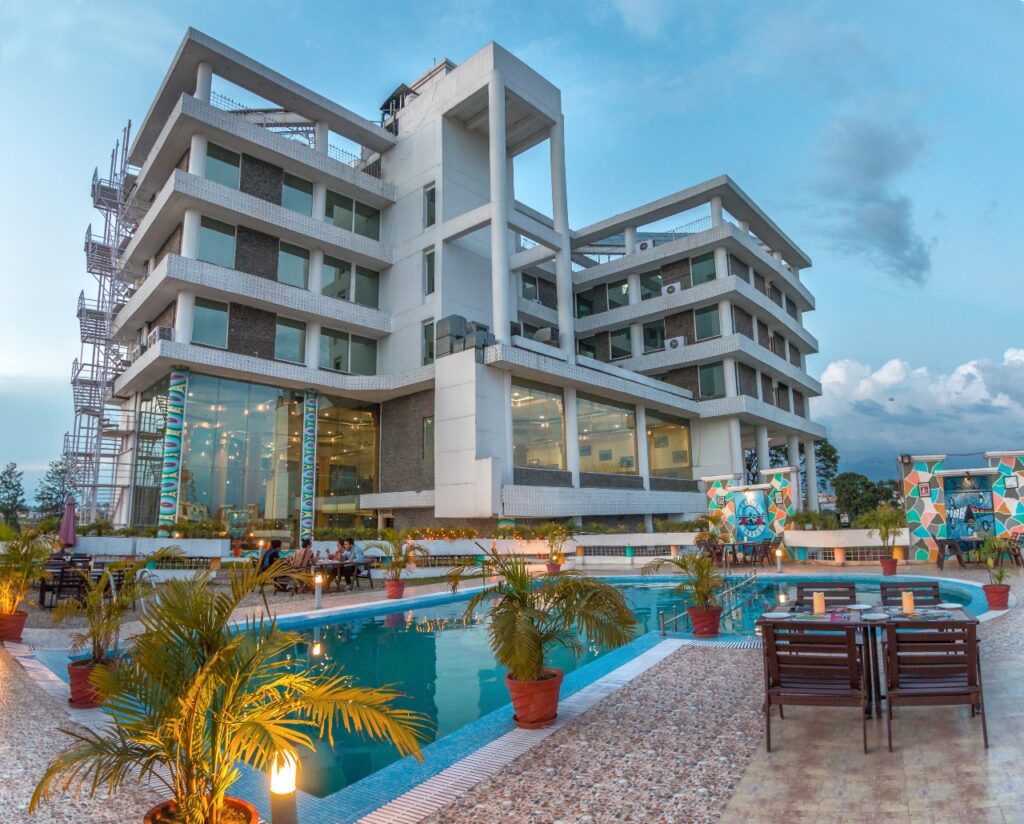 A building with a pool in front and people sitting