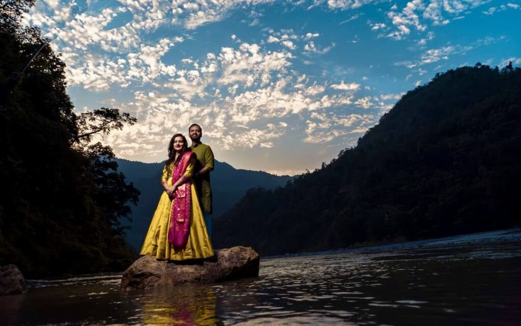 A man and woman standing in front of a mountain as their destination wedding in dehradun