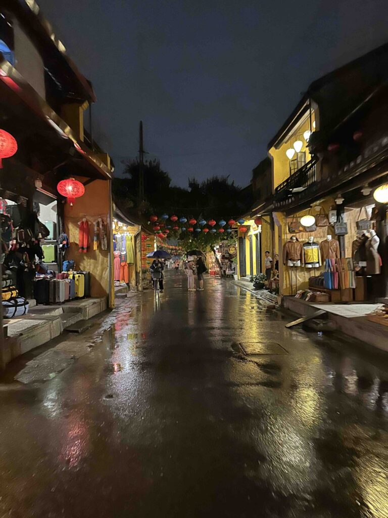 A street with rain soaked streets and lanterns.