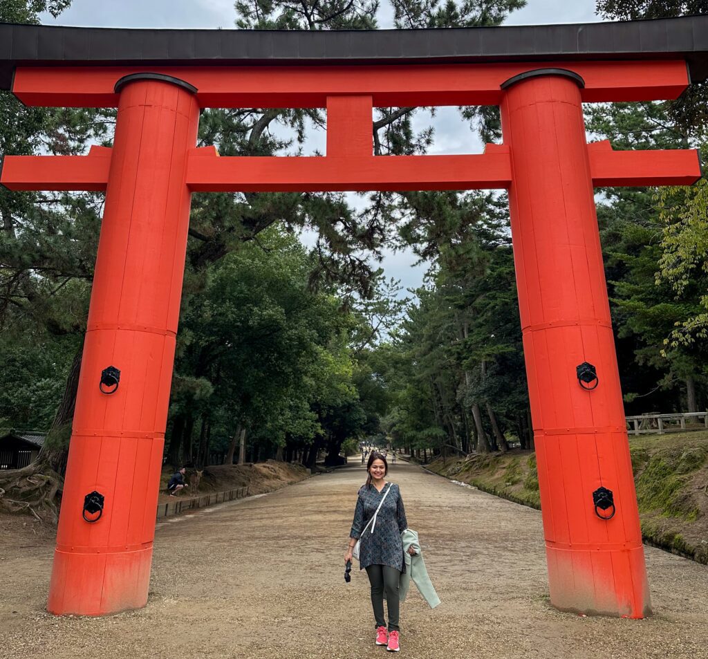 A girl standing in front of gate of a shrine in japan