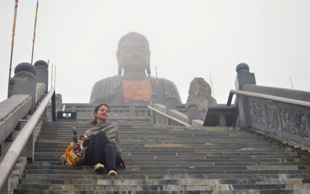 A person sitting in Fansipan legend under the amitabha buddha statue. A part of Sapa Itinerary