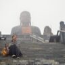 A person sitting in Fansipan legend under the amitabha buddha statue. A part of Sapa Itinerary