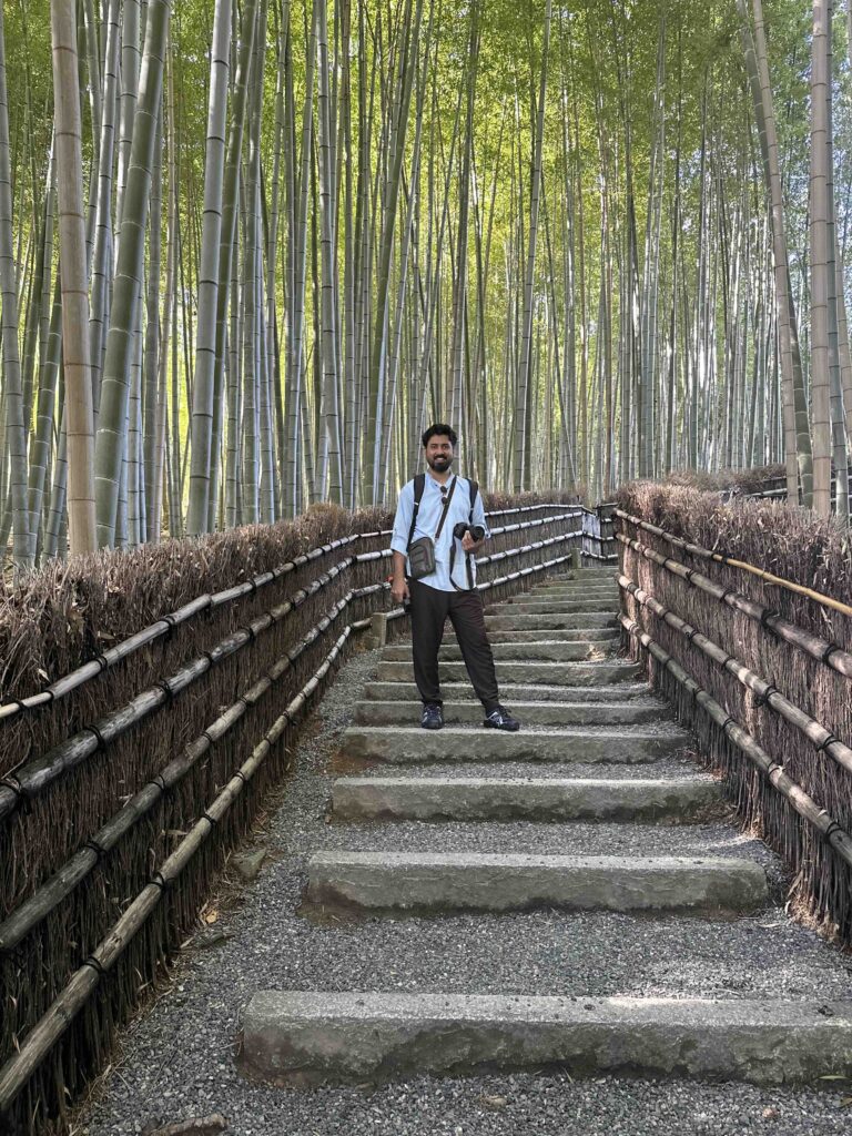 A person wearing light blue shirt standing at the Adashino Bamboo Forest in Japan.